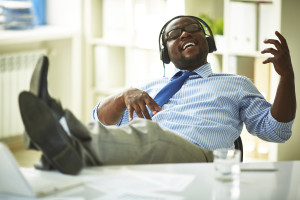 Image of young businessman taking pleasure in listening to his favourite music in office